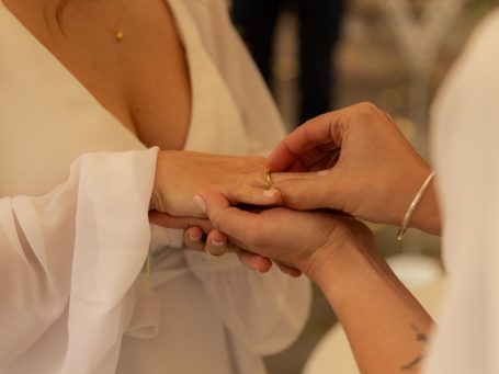 Eine Person steckt einer anderen einen Ring an den Finger während einer Zeremonie.